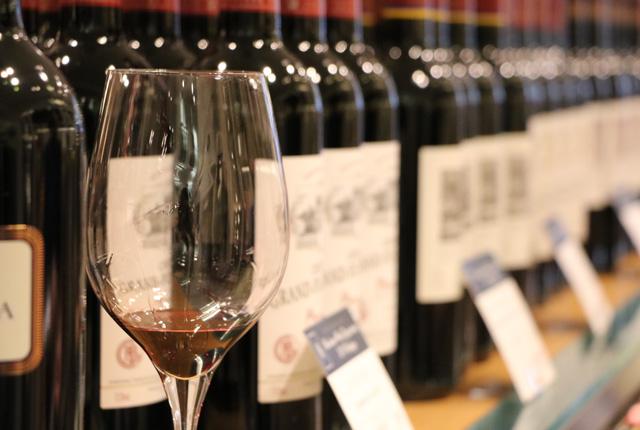 ずらっと並んだボルドーワインのボトルと赤ワインが注がれたグラス